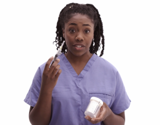 Woman in nurse's scrubs stands in front of a blank white background holding a specimen cup and a syringe