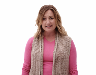 Woman with exasperated expression wears pink shirt and crotched vest in front of blank white background